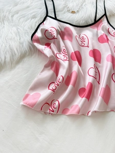 Detailed view of pink satin camisole with red heart patterns and black lace trim