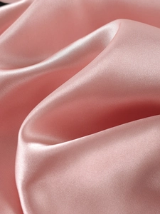 Detail of premium rose pink satin fabric showing silky smooth texture and natural drapes