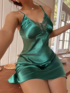 Close-up of dark green silk satin nightdress with delicate lace trim on V-neckline
