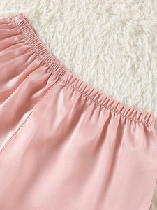 Close-up of pink satin pajama shorts with elastic waistband and smooth silk texture