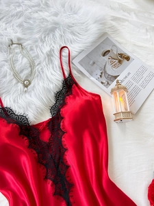Détail d'une nuisette en satin rouge avec décolleté en V et dentelle noire sur fond en peluche
