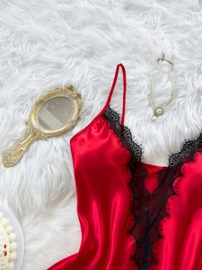 Détail de la nuisette en satin rouge avec dentelle noire et collier de perles sur fourrure