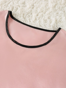 Detail of pink satin pajama top showing high-quality black piping on the round neckline