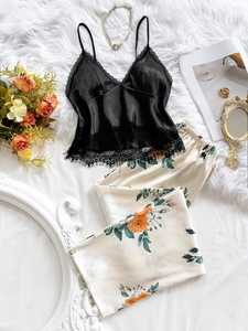Flat lay of women's silk pajama set with black lace camisole and floral print trousers