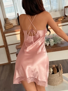 Detail of pink satin nightdress featuring cross straps and exquisite lace hemline