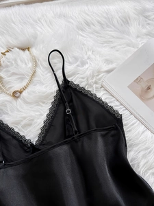 Detail of black silk camisole with delicate eyelash lace trim on soft white plush rug