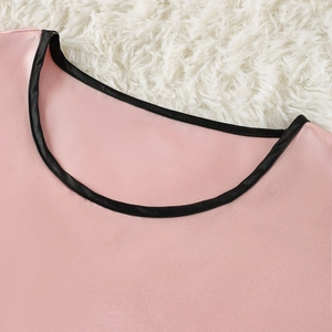 Pink satin pajama top with black trim on soft white faux fur background