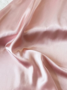 Close-up of soft pink satin fabric with a silky smooth texture and pearlescent luster