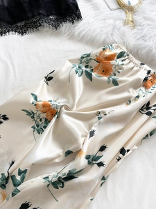 Detail of silk satin pajama pants featuring orange rose floral prints and elastic waist