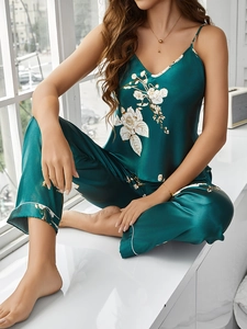 Detail eines dunkelgrünen Seiden-Pyjama-Sets mit Blumendruck und weißen Paspel-Akzenten