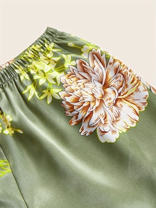 Detailed view of dark green silk satin pajama shorts with floral print and elastic waist