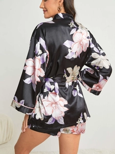 Détail du peignoir en satin noir à fleurs avec une texture lisse et des motifs vifs