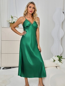 Close-up of elegant dark green satin nightgown with lace V-neckline detail in home setting