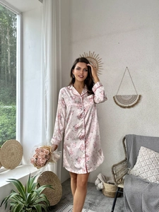 Dettaglio di camicia da notte in seta con motivo floreale e piping rosso su un abito a camicia