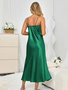 Detail of the emerald green satin slip dress featuring thin straps and smooth texture