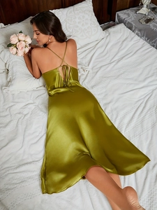 Close-up of green satin backless slip dress with elegant criss-cross tie detailing