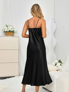 Detail of the back view of a black satin slip dress showing slim straps and draped fabric