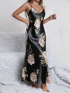 Detail of elegant black satin nightgown featuring large floral prints and thin straps