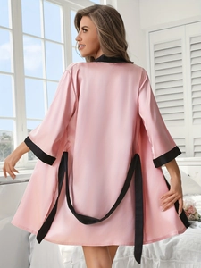 Détail du peignoir en satin rose avec ceinture noire en soie et bordure noire