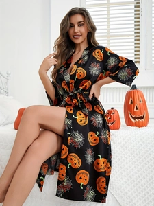 Detail of Halloween robe showing orange pumpkins and white cobwebs on black satin fabric