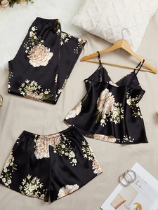Detail of silk-satin pajamas set with elegant golden floral patterns on black fabric