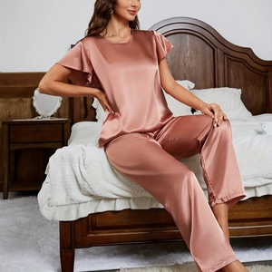 Γυναικείες σατέν πιτζάμες σε dusty rose με βολάν στα μανίκια και μακρύ παντελόνι στο υπνοδωμάτιο