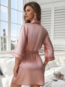 Détail d'un peignoir en soie rose avec ceinture et finitions passepoilées aux poignets