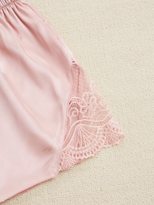 Détail du pyjama en satin rose avec bordure en dentelle florale sur fond en maille douce