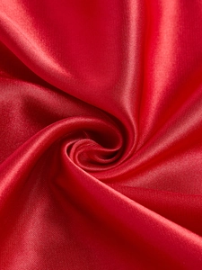 Vue macro détaillée montrant la texture lisse et l'éclat de soie du tissu en satin rouge