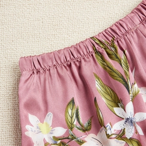 Pyjama floral en soie rose avec détail de taille élastique sur un tapis en osier tressé