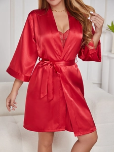 Gros plan détaillé d'un peignoir en satin rouge avec dentelle et ceinture nouée