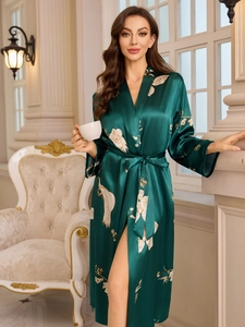 Close-up of luxury dark green silk robe with golden floral peacock print and waist tie