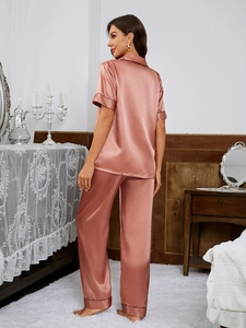 Close-up of pink satin pajama set featuring black contrast piping and silky texture fabric