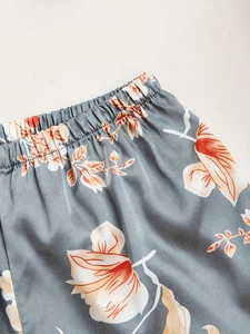 Close-up of elastic waistband and floral satin fabric on grey three-piece pajama set