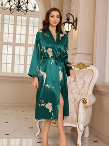 Detail of emerald green silk satin robe featuring elegant white crane and floral patterns