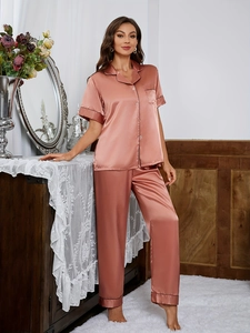 Detail of rose gold satin pajamas showing black contrast piping and chest pocket texture