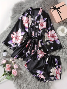 Flat lay detail of black floral satin robe and shorts set on a soft faux fur rug