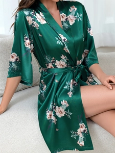 Detail of dark green silk satin robe with elegant floral patterns and a waist tie