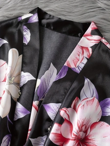 Detail view of black floral satin robe with silk-like texture on a soft plush backdrop