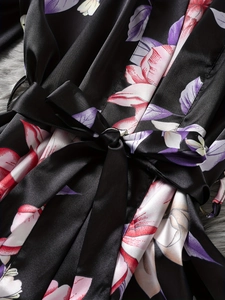 Detail of black floral satin robe showing smooth fabric texture and belted waist bow