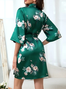 Detail of emerald green satin robe with cream floral patterns and silk texture