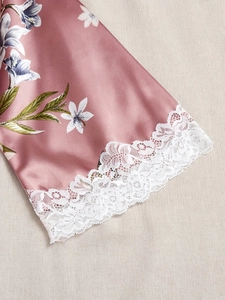 Détail de la manche en satin rose avec motif de lys blancs et bordure en dentelle