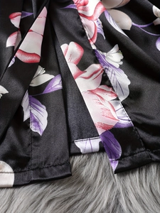 Detailed close-up of smooth black satin fabric with floral pattern on kimono robe