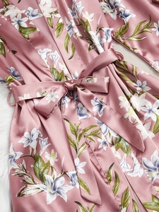 Détail du peignoir en satin rose à fleurs avec texture soyeuse et ceinture nouée