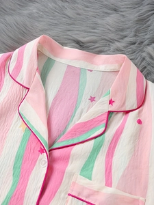Détail d'un haut de pyjama rayé rose et vert avec imprimés étoiles et passepoils