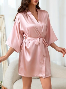 Détail d'un peignoir en satin rose avec texture soyeuse et ceinture ajustable