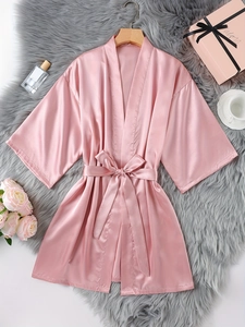 Détail d'un peignoir kimono en satin rose avec texture soie sur un tapis en peluche