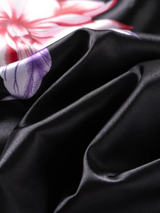 Close-up of black satin floral kimono fabric showing smooth texture and lily print detail