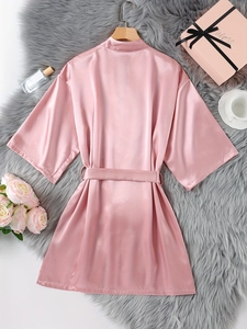 Peignoir en satin de soie rose sur tapis en fourrure avec boîte cadeau et roses