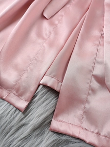 Détail de l'ourlet du pyjama en satin rose avec coutures lisses sur fond en fausse fourrure
